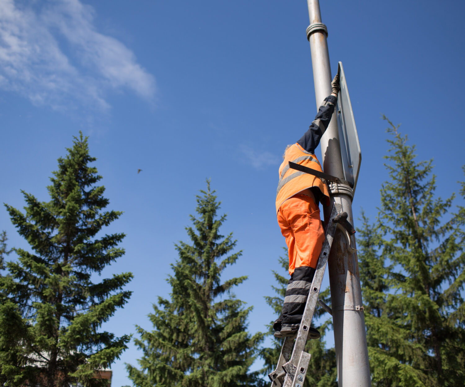 Installation road sign on pole. Road worker sets sign.